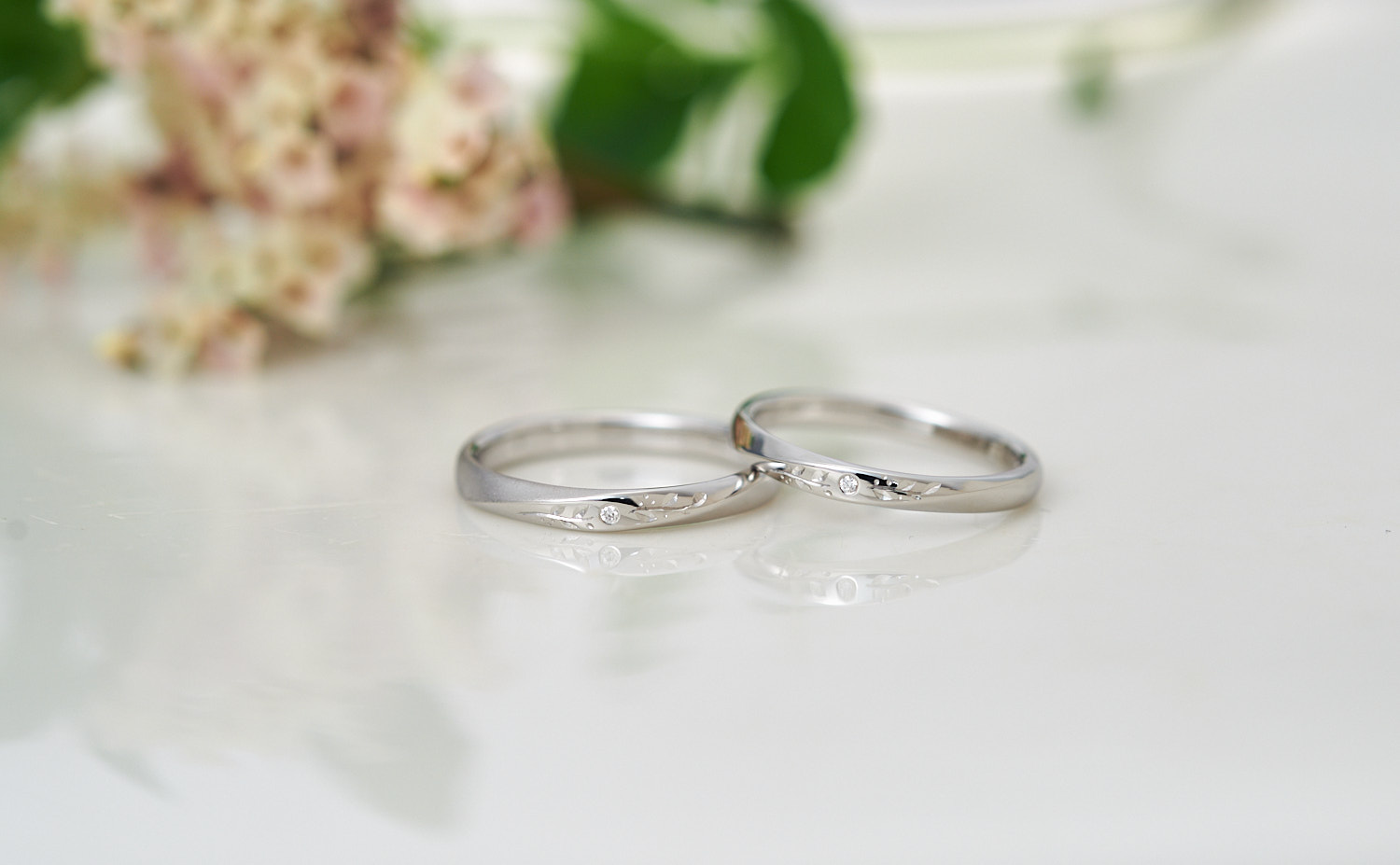 草花彫りとダイヤモンドが輝く捻りのプラチナ結婚指輪
